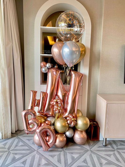 Rose gold, gold, and silver balloon arrangement with letter balloons, helium balloons, and confetti bubble balloon
