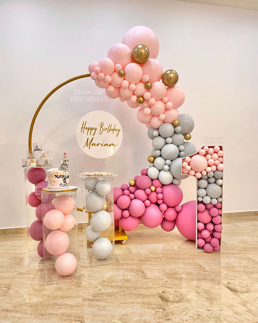 Pink, grey, and gold birthday balloon backdrop with circular frame, number display, and custom text sign