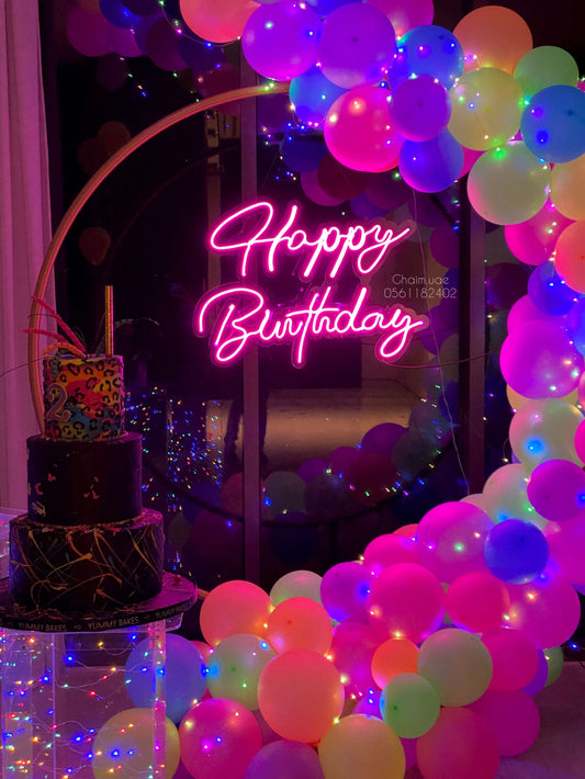 Neon birthday balloon backdrop with vibrant neon balloons, LED fairy lights, and pink “Happy Birthday” sign