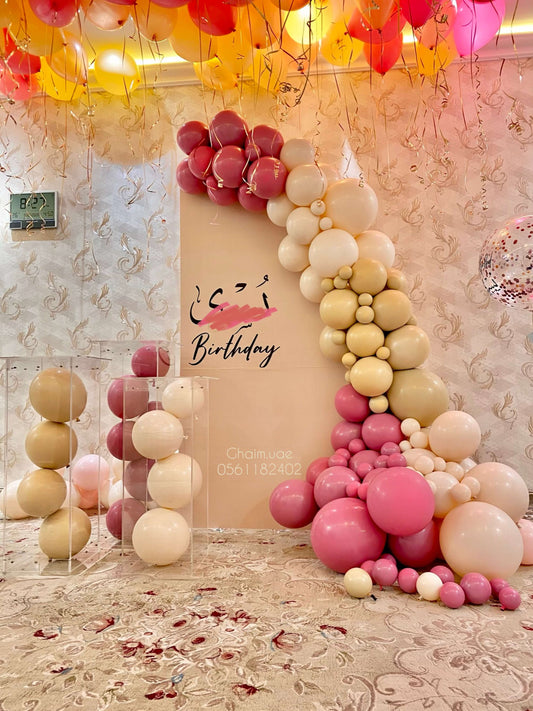 Cream, pink, and gold balloon backdrop with ceiling balloons and custom text sign