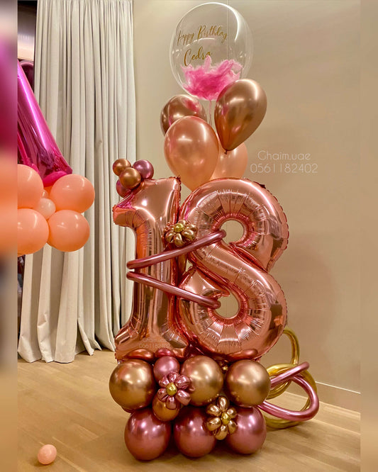 Rose gold and gold balloon arrangement with number balloons, custom text bubble balloon, and floral accents