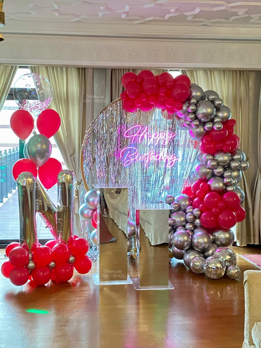 Red and silver birthday balloon backdrop with neon sign, letter balloon, and custom text setup