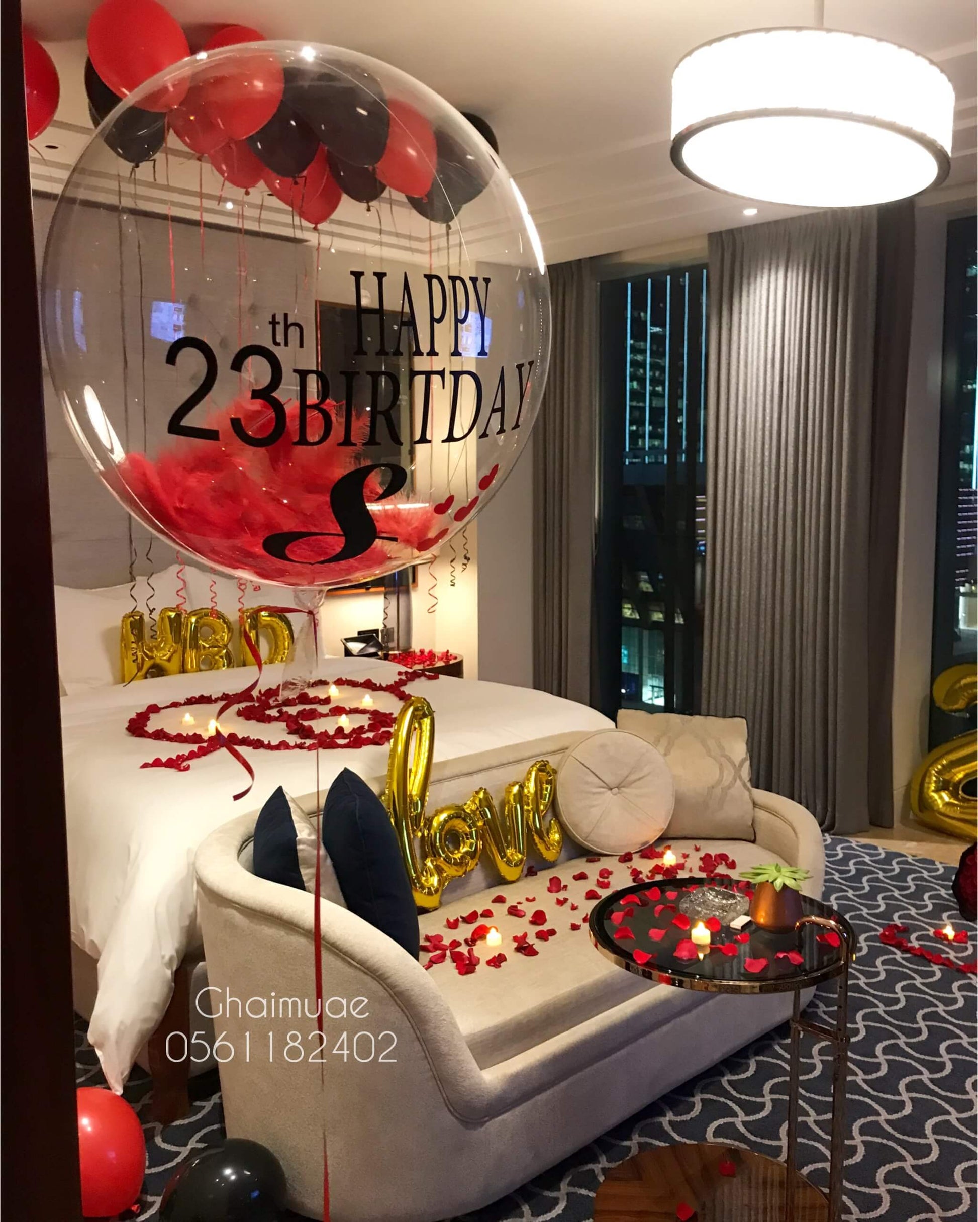 Luxury romantic birthday room decor with black and red balloons, gold numbers, and rose petals Dubai UAE